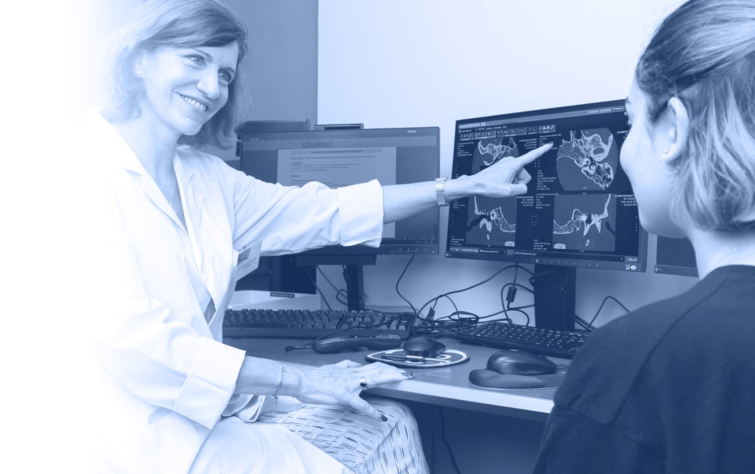 Femme docteur pointant du doigt des radios sur un écran d'ordinateur.